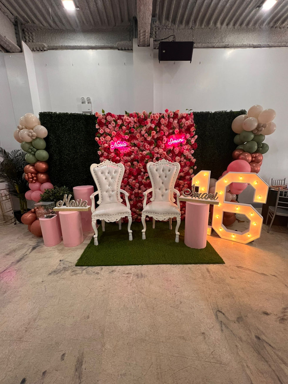 two chairs are sitting in front of a wall of flowers and balloons