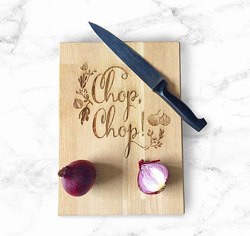 Cutting board engraved with 'Chop-chop', accompanied by a knife and a sliced red onion.