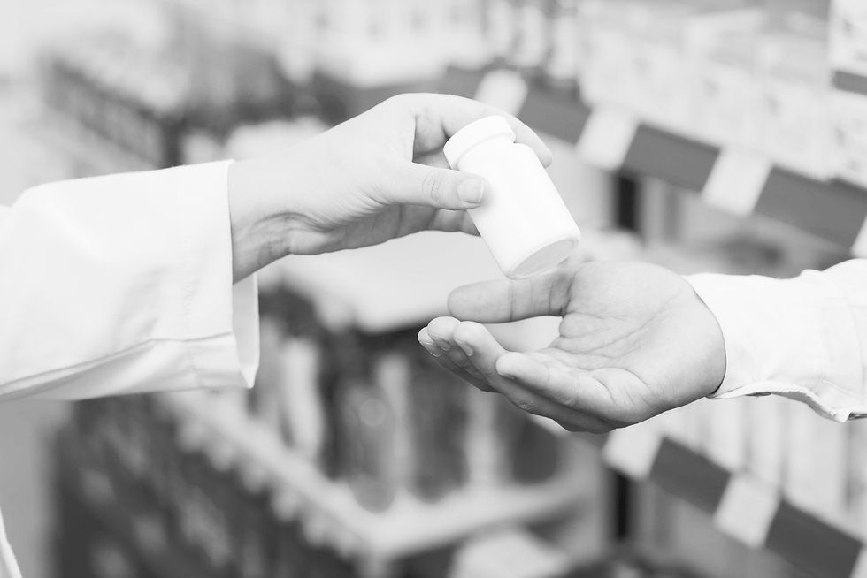 pharmacist handing a white pill bottle to a customer