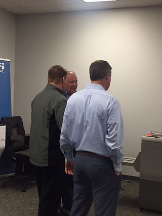 Three men in a room discussing business, sharing ideas together.