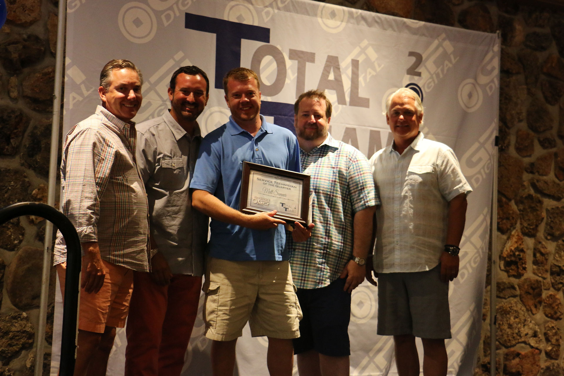 Group holding certificate in front of a Total 2020 background. 5th Color. GO BEYOND CMYK.