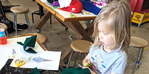 Girl cutting material for her trash fashion garment. 