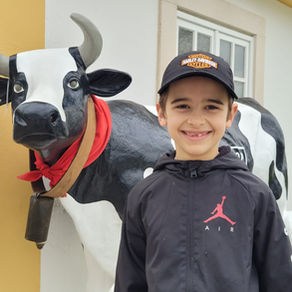 Boy in front of a lifesize statute of a cow.