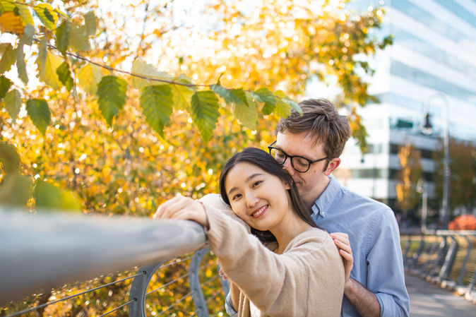Young couple smiling on bridge with fall foliage in background