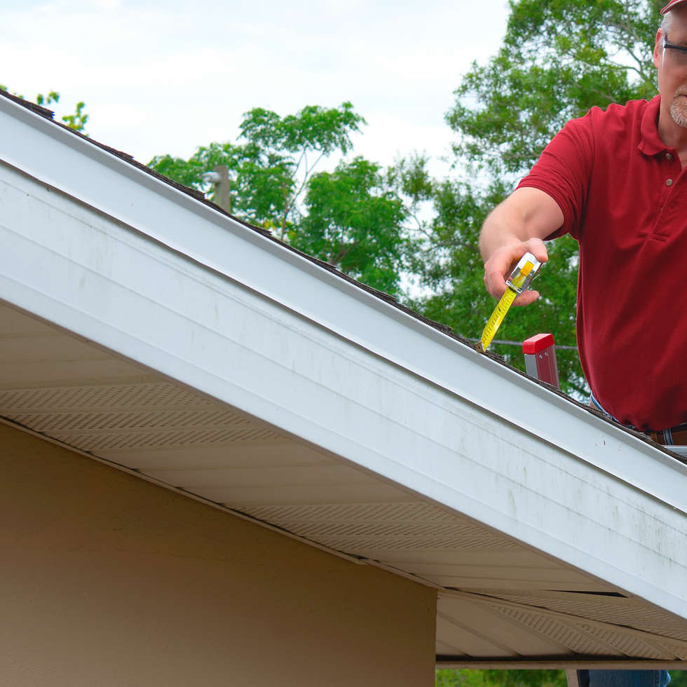 Man measuring gutter on a house