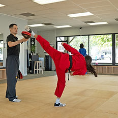Private Training student kicking towards paddle being held up in the air.