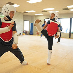 Martial arts students practice high kicks in class