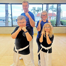 A family of four (father, mother, son, daughter) standing with fists up standing in a studio.