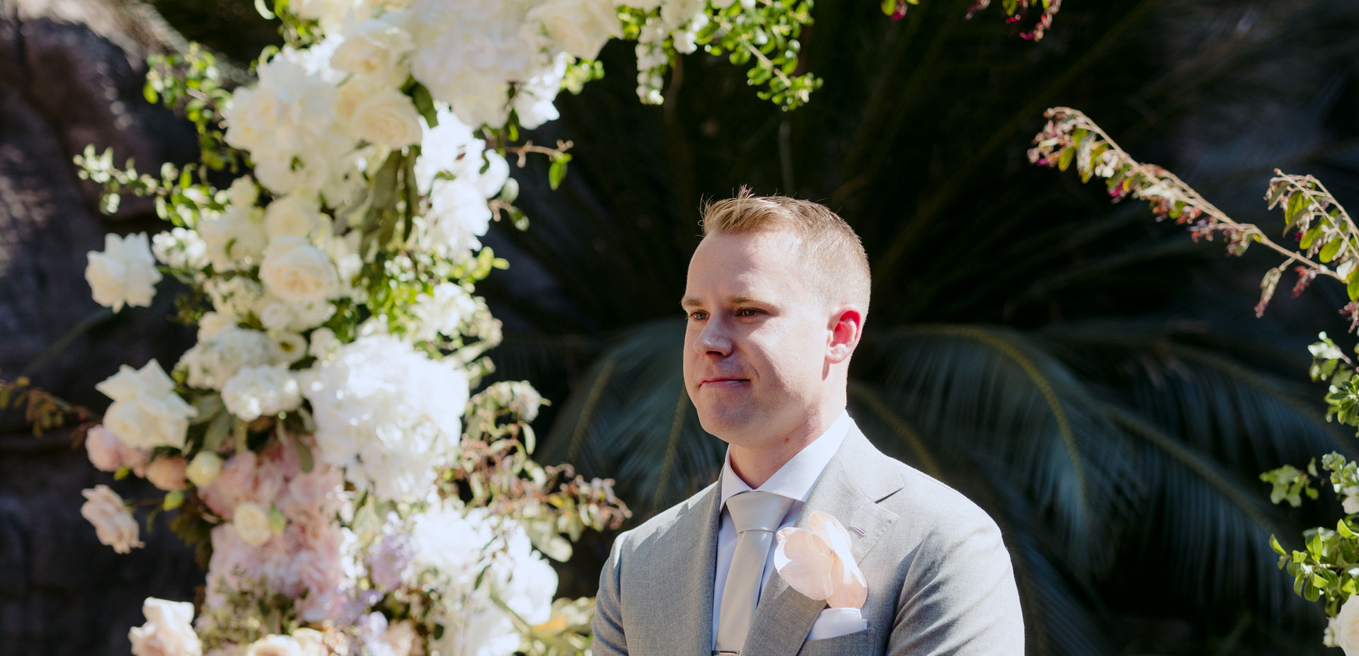 Groom standing at floral arbour in the Rock Cathedral at KVBR.
