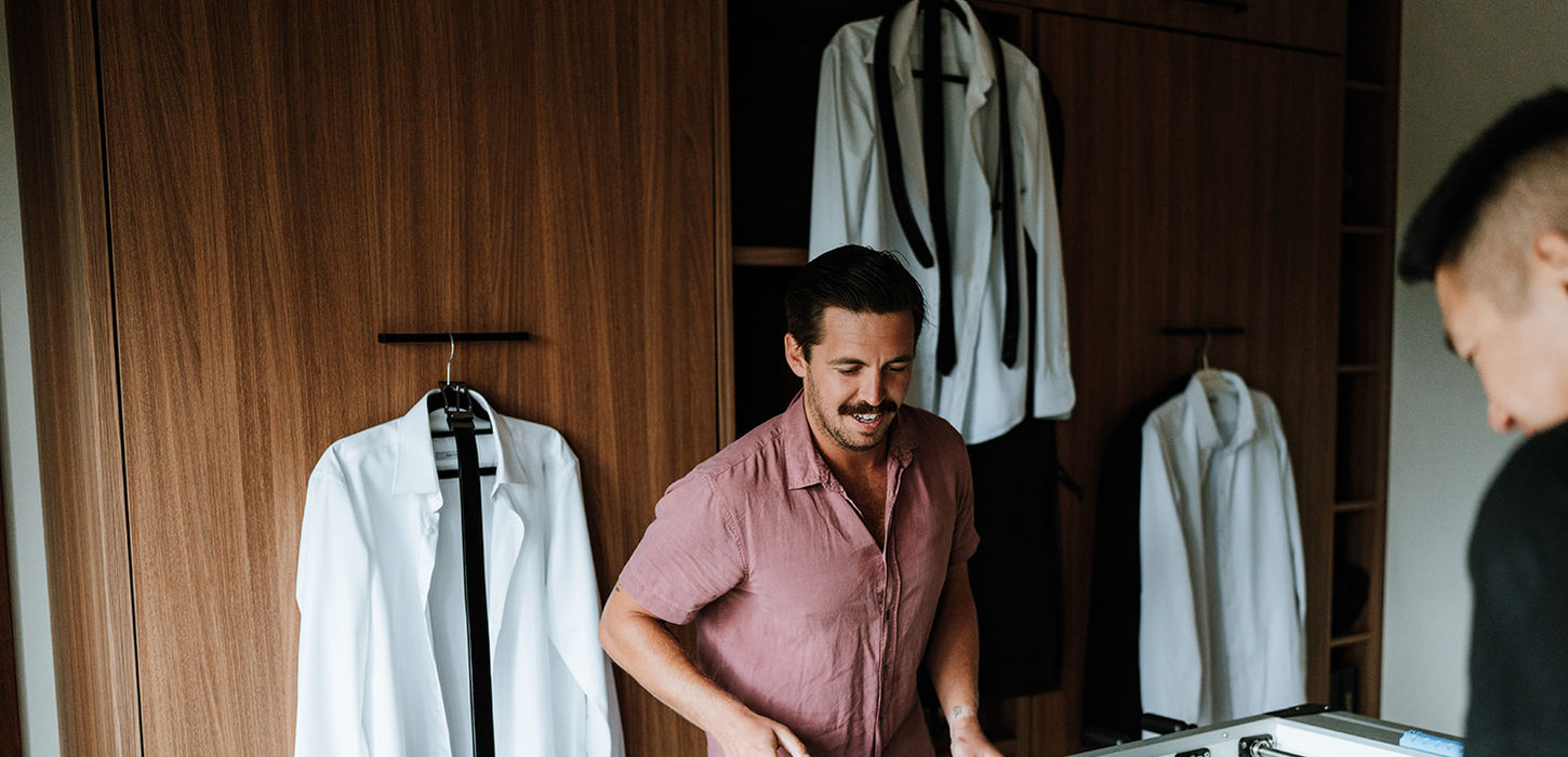 Groom in the suite with foosball table and wedding shirts hanging at KVBR.