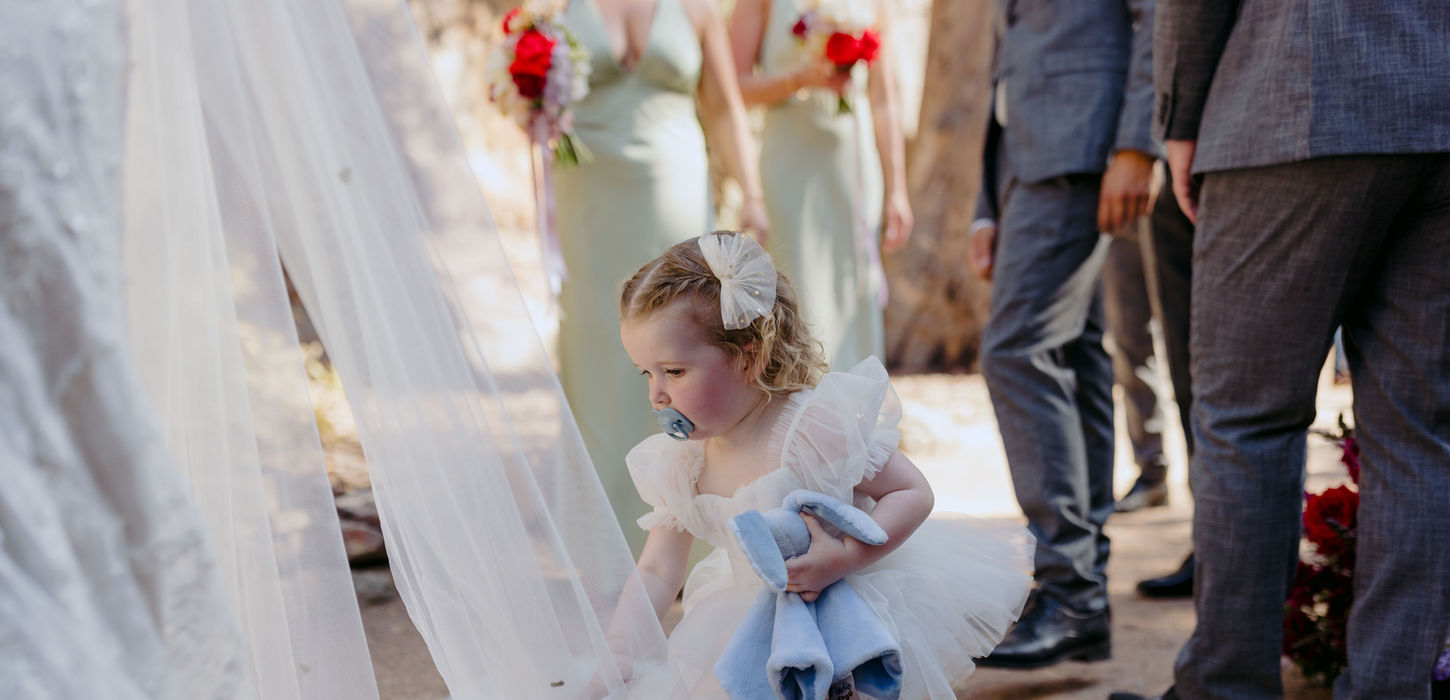 Flower girl playing with wedding veil during ceremony at KVBR Rock Cathedral.