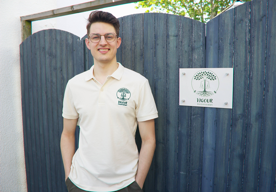 Founder and Senior Physiotherapist Max Ankerstjerne standing outside the clinic next to Vigour Physiotherapy logo.
