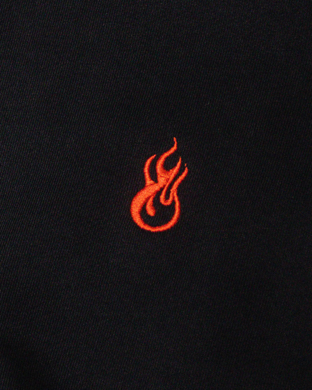 Logo ngọn lửa thêu màu cam nổi bật trên nền vải đen.