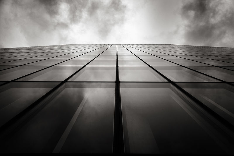 grayscale-low-angle-shot-skyscraper-wall-with-glass-windows-cloudy-sky.jpg