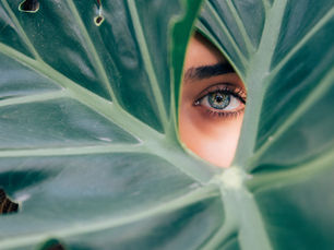 girl peeking through green leaf