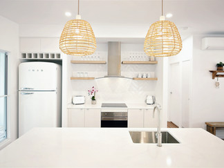 The newly renovated kitchen with a fresh white design, complemented by a stylish fridge and soft wooden highlights for a warm, contemporary feel.
