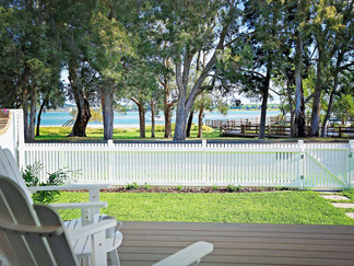 Deck chairs overlooking the deck and white picket fence with a view of the beach.
