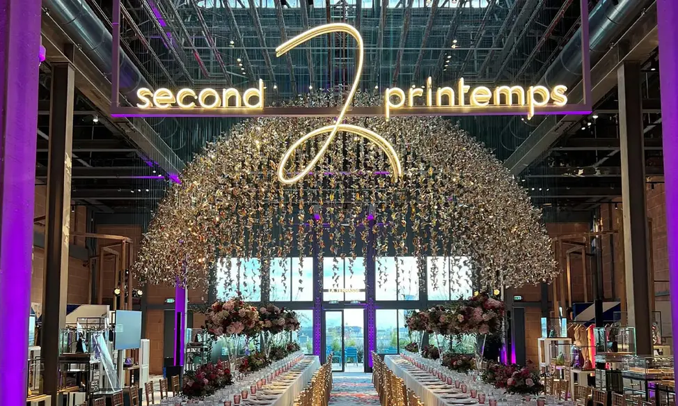 Dîner assis sur longues tables fleuries sous les origamis du Pont d'Argent, au 7e Ciel du Printemps Haussmann à Paris 9e.