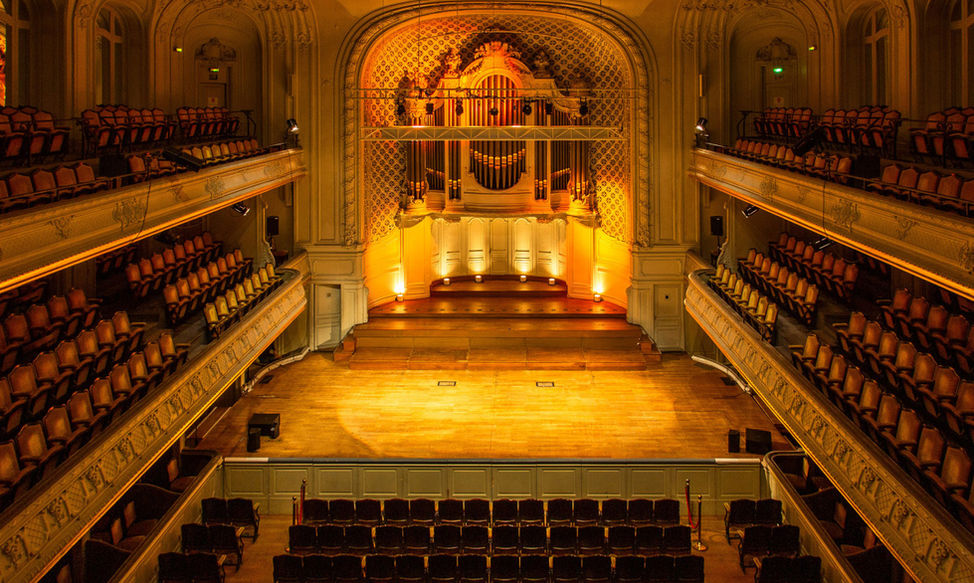 Vue plongeante sur la grande salle de la Salle Gaveau, parterre de fauteuils et scène baignée de lumière dorée