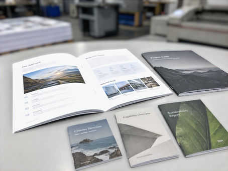 Open and closed multi-page sales booklets displayed on a worktable in a commercial print production shop