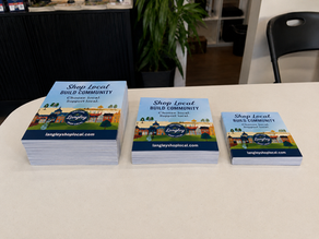 Three stacks of colourful 5x7 handout cards in different quantities on a table, representing small business printing in Langley, BC.
