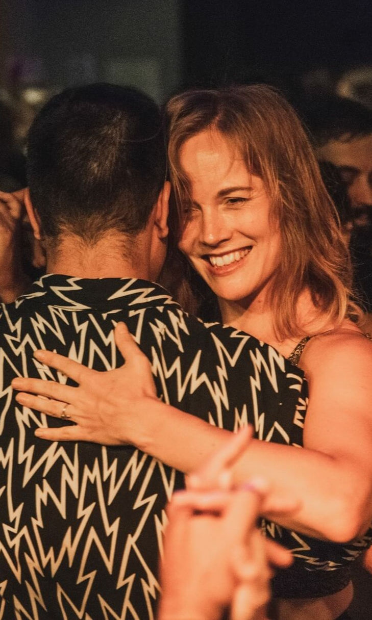 Ragazza che balla in abbraccio stretto in una milonga affollata di Buenos Aires.