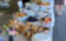 Eye-level view of a beautifully set outdoor brunch table by the bay with sunlight reflecting on the water