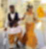 A couple in traditional attire walks hand in hand. The woman holds a yellow feather fan. Elegant setting with decorative patterns.