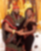 A couple wearing a striking black velvet outfit hand-embroidered with bold, colorful patterns that resemble