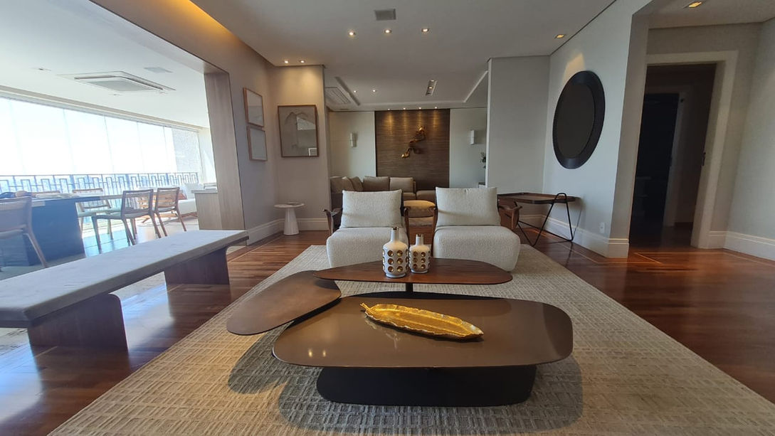 Living amplo do apartamento no Parque Cidade Jardim com piso de madeira e iluminação natural.