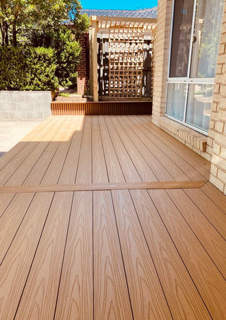 Wooden deck beside brick house and window.