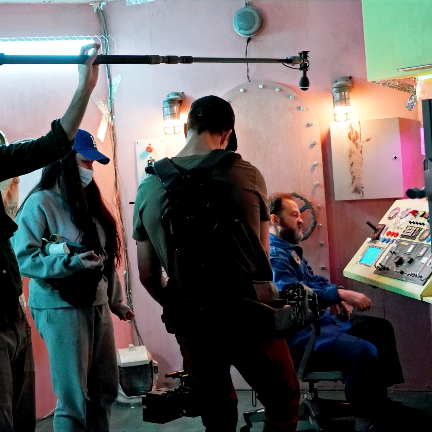 Film crew of three filming man in spaceship control station