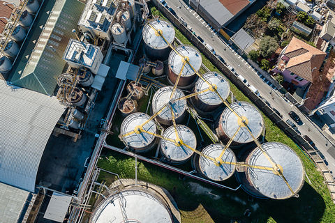 Vista aerea dell’impianto IP di Savona con serbatoi industriali e panorama costiero, fotografia industriale e corporate in Liguria, energia e infrastrutture.
