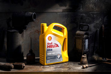 Fotografia industriale del prodotto Shell Helix HX6 realizzata da Studio Bozzini Milano – still life di olio motore ambientato in officina con luce drammatica.