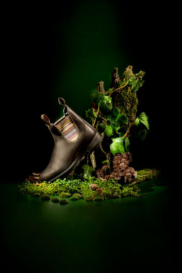 Stivale Blundstone fotografato su set naturale con muschi e radici – Studio Bozzini Milano, fotografia still life moda e outdoor con luce artistica.