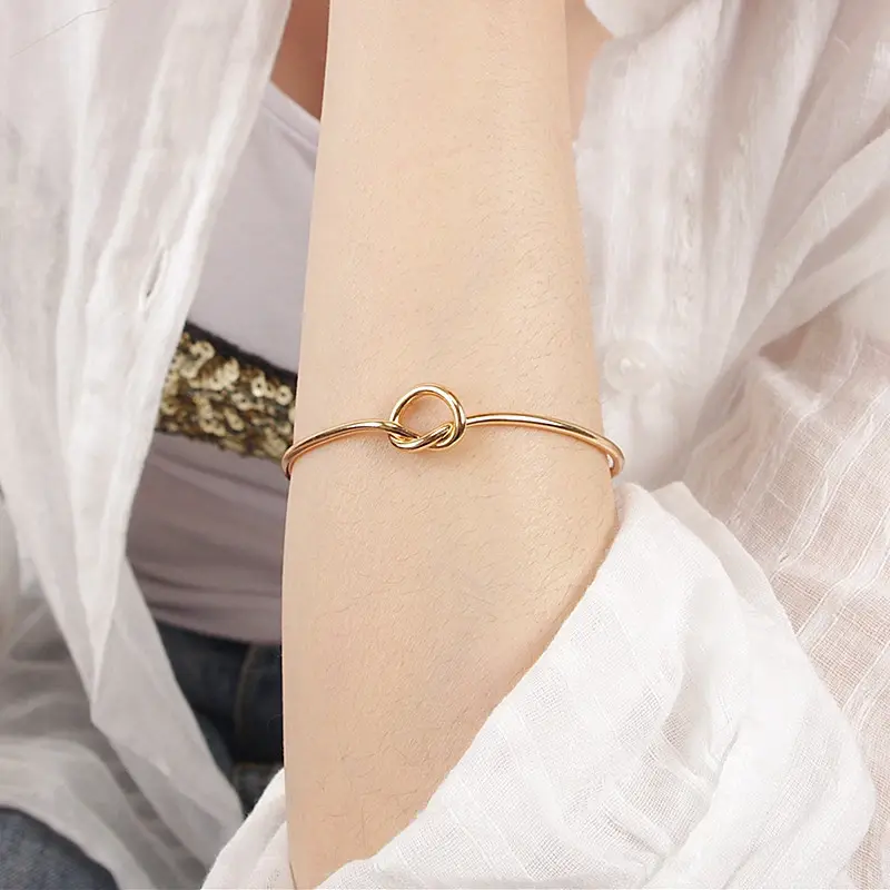 Thumbnail: gold colour love knot bangle on a ladies wrist