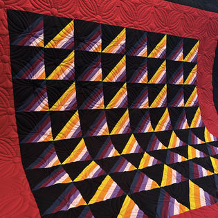 Amish Shadows quilt with vibrant solid fabric strips, black triangles, and Vienna pantograph longarm quilting by High Rock Quilter.