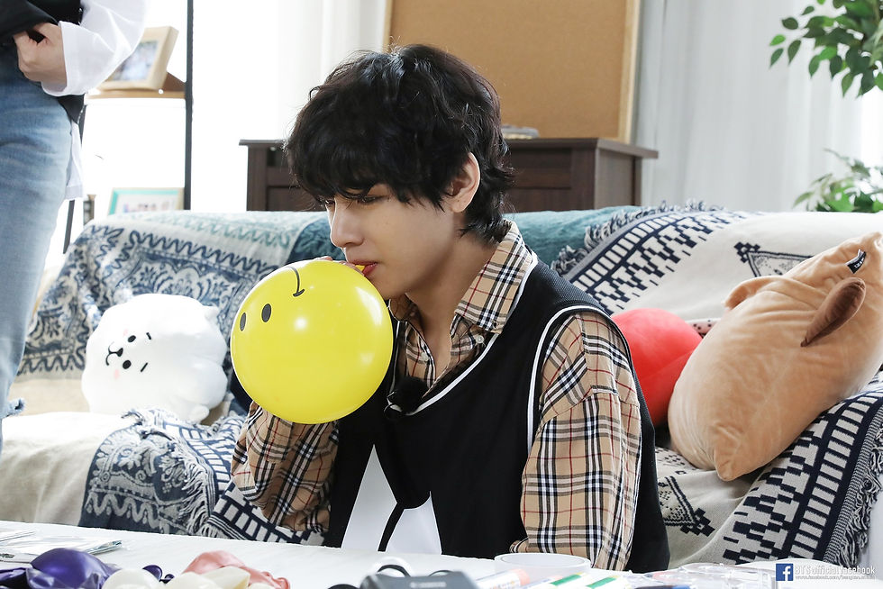 A man in a plaid shirt blowing a balloon