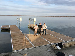 3 boys standing on a dock in the lake