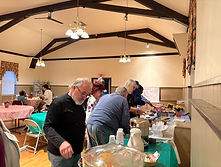 Crowd of people featured at a food table at an event in the Memorial Church of St. Luke Parish Hall