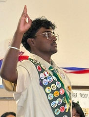 A well decorated Boy Scout standing with the Scout sign at an award ceremony