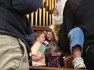 A young church member and their adult singing from the hymnal