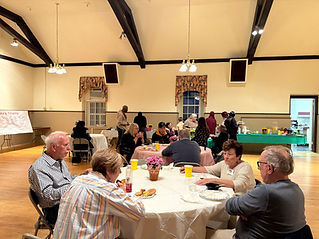 Multiple tables in the Parish Hall full of members for a community event