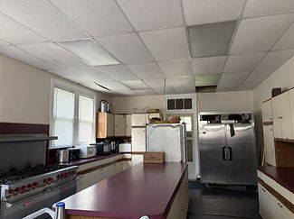 The Parish Hall kitchen equipped with a long counter, large refridgerator, stove, and oven