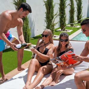 Two women relaxing in a cabana by the pool in stylish swimsuits at their Miami bachelorette