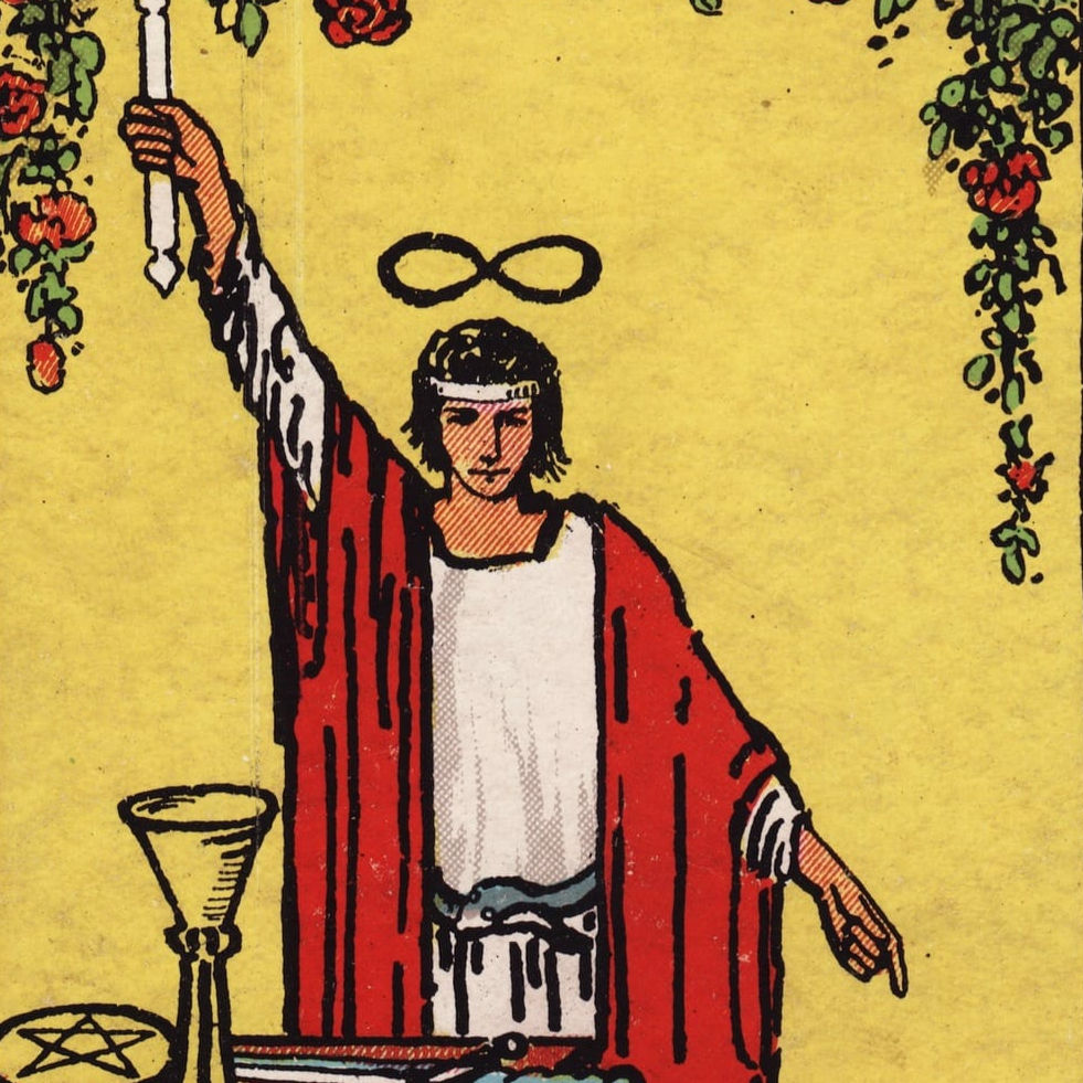 yellow background with a young man in the foreground holding a white candle lit on both ends. He is dressed in white clothes and a red cloth around his shoulders, a blue snake like belt. There is an infinity sign above his head, as well as red and green vines. Below him is a yellow cup, yellow pentacle, and gray sword on a brown table.