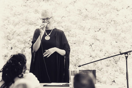 Rednerin spricht ins Mikrofon bei Freier Zeremonie, Traumhochzeit im Freien. Speaker speaks into microphone at outdoor ceremony, dream wedding outdoors.