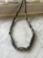a surfer necklace beaded with long black horn and green bone beads