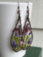 long glass bead earrings with a green and purple flower garden wrapped inside copper wire butterfly wings