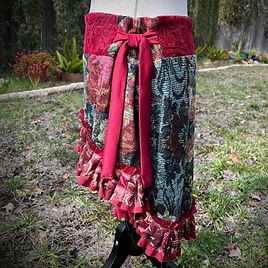side view of a festival skirt made of red and black floral cotton fabric has a coral chiffon and lace ruffle along a pirate wench hem